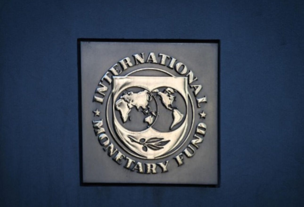 Primer plano del logotipo metálico del Fondo Monetario Internacional (FMI) sobre una pared azul, en el contexto de su advertencia sobre los impuestos a la energía.