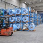 Interior de un almacén industrial logístico en Castilla-La Mancha con estanterías azules llenas de bobinas de acero envuelvas y una carretilla elevadora en primer plano.