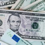 Primer plano de billetes de 50 y 5 dólares estadounidenses mezclados con billetes de 50 y 100 euros, representando la conversión de divisas en el comercio exterior.