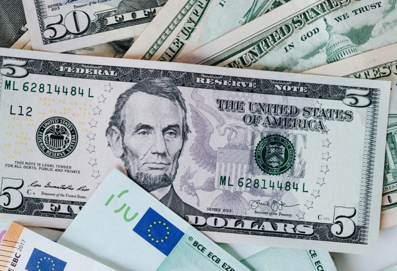 Primer plano de billetes de 50 y 5 dólares estadounidenses mezclados con billetes de 50 y 100 euros, representando la conversión de divisas en el comercio exterior.