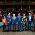 Representantes de la dirección de Globalcaja, ponentes del evento y miembros del Consejo Rector posando alineados en el escenario del Teatro Circo de Albacete ante un patio de butacas lleno de asistentes.